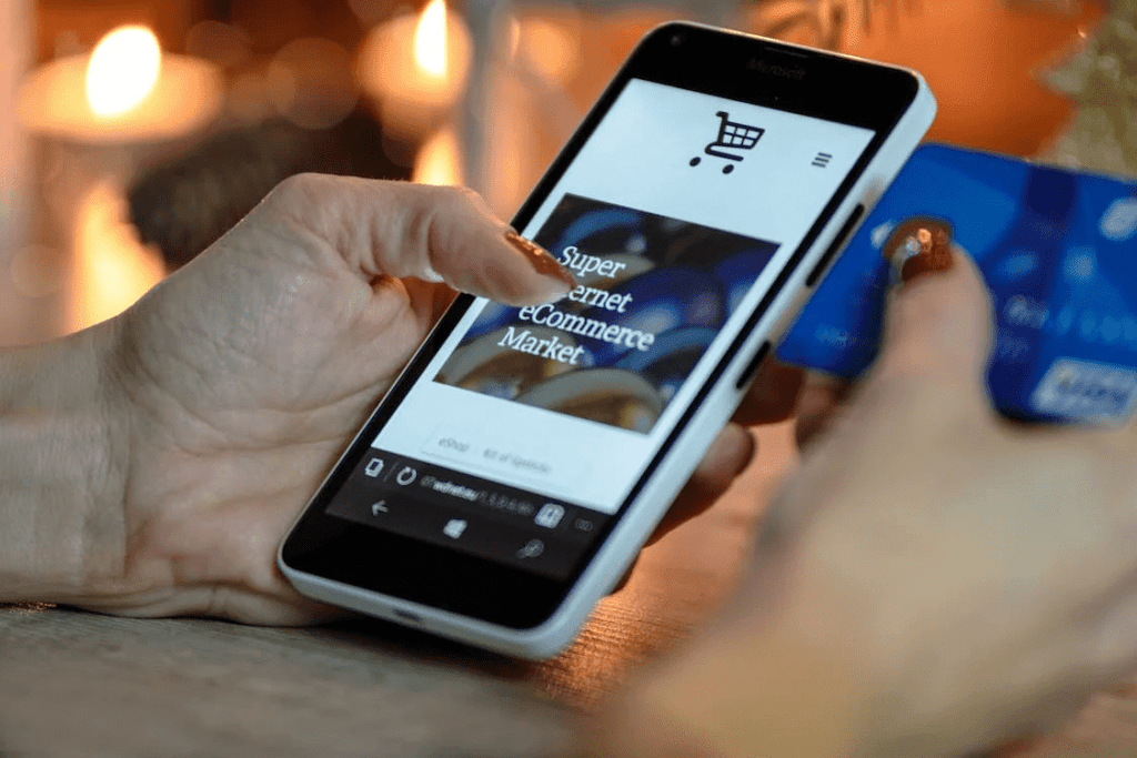 A woman is using WooCommerce on her smartphone to make a payment with a credit card for a service business.