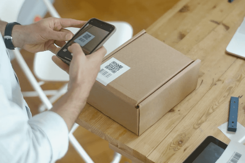 A man is using a cell phone to scan a WooCommerce qr code on a box.